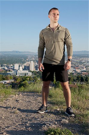 running man - Portrait of young male runner on dirt track above city in valley Stock Photo - Premium Royalty-Free, Code: 614-08202044