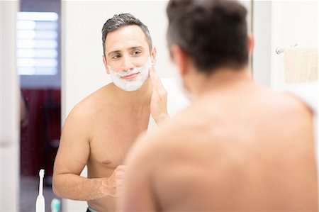 simsearch:649-08179955,k - Mid adult man, looking in mirror, applying shaving foam to face, rear view Fotografie stock - Premium Royalty-Free, Codice: 614-08202087