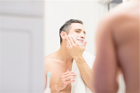 simsearch:649-08179955,k - Mid adult man, looking in mirror, applying shaving foam to face, rear view Fotografie stock - Premium Royalty-Free, Codice: 614-08202088