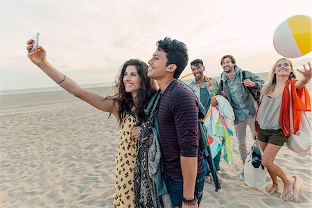 simsearch:614-08202219,k - Group of friends walking along beach, young couple taking self portrait with smartphone Fotografie stock - Premium Royalty-Free, Codice: 614-08202213