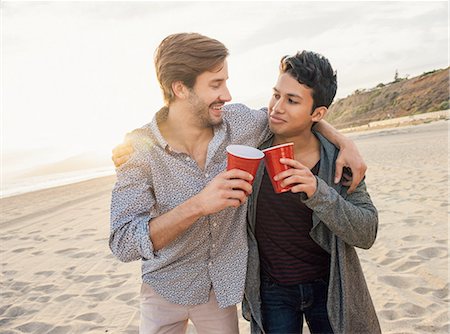 simsearch:614-08202287,k - Two male friends having drinks together on beach, arms around each other Fotografie stock - Premium Royalty-Free, Codice: 614-08202228