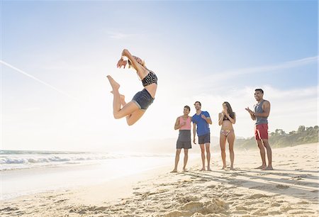 simsearch:614-08202219,k - Group of friends on beach watching friend leap in air Fotografie stock - Premium Royalty-Free, Codice: 614-08202261