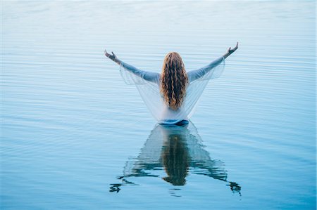 redhead female spiritual - Rear view of young woman standing in blue lake with arms open Stock Photo - Premium Royalty-Free, Code: 614-08202298