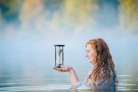 simsearch:614-08487980,k - Young woman standing in misty lake gazing at hourglass Stock Photo - Premium Royalty-Free, Code: 614-08202307