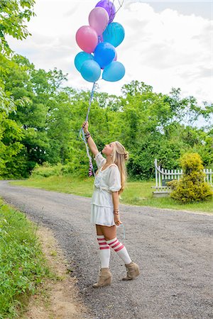 simsearch:614-08119768,k - Young woman gazing up at bunch of balloons on rural road Stock Photo - Premium Royalty-Free, Code: 614-08202315