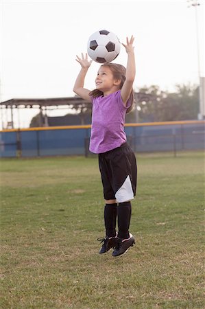 simsearch:614-08219838,k - Girl jumping and heading football on practice pitch Foto de stock - Sin royalties Premium, Código: 614-08219846
