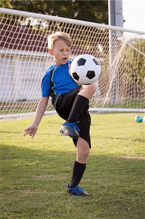 simsearch:614-08219838,k - Boy playing keepy uppy with football on pitch Foto de stock - Sin royalties Premium, Código: 614-08219842