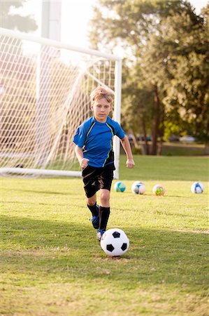 simsearch:614-08219838,k - Boy running with football on practice pitch Stock Photo - Premium Royalty-Free, Code: 614-08219843