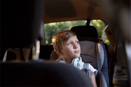 Boy in car back seat gazing out through window Stock Photo - Premium Royalty-Free, Code: 614-08219858