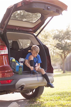 Boy football player sitting in car boot tying football boot laces Stock Photo - Premium Royalty-Free, Code: 614-08219850