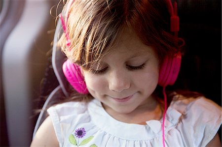 Close up of girl wearing pink headphones in car Stock Photo - Premium Royalty-Free, Code: 614-08219865