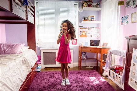Girl in bedroom singing into microphone and dancing Fotografie stock - Premium Royalty-Free, Codice: 614-08219932