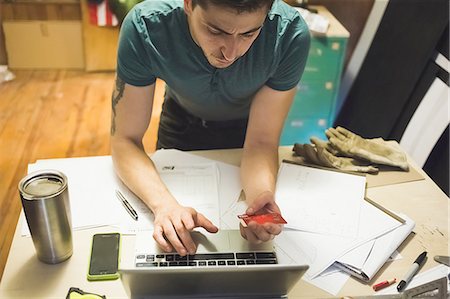 supply - High angle view of young man using credit card and laptop to make online purchase Stock Photo - Premium Royalty-Free, Code: 614-08220086