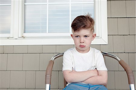 portrait boy arms crossed - Portrait of boy sitting outside house sulking Stock Photo - Premium Royalty-Free, Code: 614-08270203
