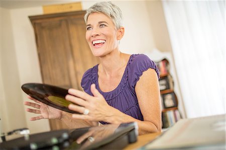 Happy mature woman playing vinyl records Stock Photo - Premium Royalty-Free, Code: 614-08270219