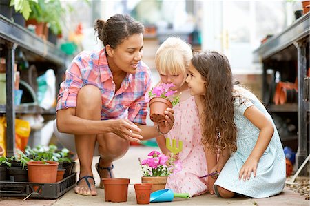 Mid adult woman and two girls smelling flower pots in greenhouse Photographie de stock - Premium Libres de Droits, Code: 614-08270227