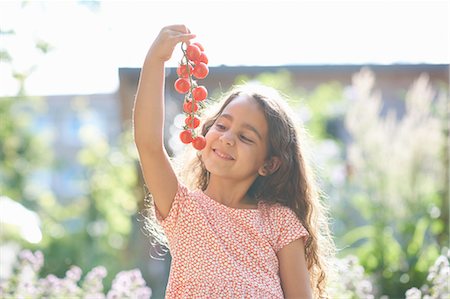 Portrait of girl holding up bunch of cherry tomatoes in garden Photographie de stock - Premium Libres de Droits, Code: 614-08270231