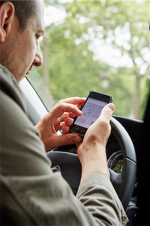 Mid adult man sitting in car, looking at map on smartphone Stock Photo - Premium Royalty-Free, Code: 614-08270243