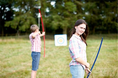 Portrait of teenage girl practicing archery with brother Foto de stock - Royalty Free Premium, Número: 614-08270382