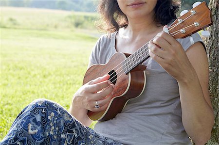 pictures of ethnic woman playing ukulele - Cropped image of woman in field playing ukuele Stock Photo - Premium Royalty-Free, Code: 614-08270400