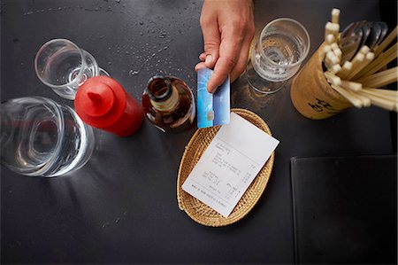 people holding cards in hand - Overhead view of man paying with credit card Photographie de stock - Premium Libres de Droits, Code: 614-08270421