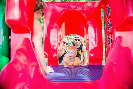 simsearch:614-02640837,k - View through playground equipment of mother and father encouraging baby boy Stock Photo - Premium Royalty-Free, Code: 614-08270494