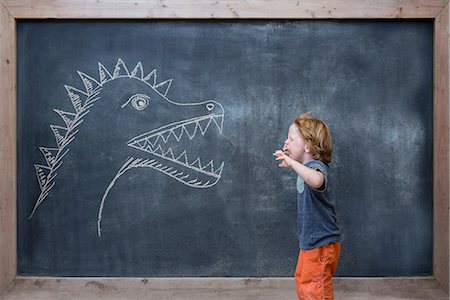 Young boy roaring at dinosaur drawing on blackboard Photographie de stock - Premium Libres de Droits, Code: 614-08307596