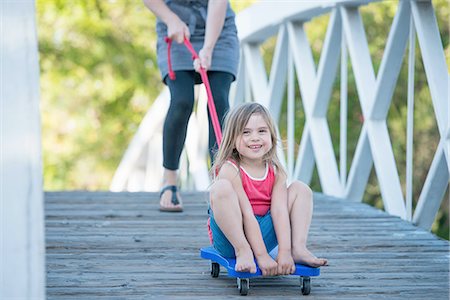 sich herumwälzen - Young girl sitting on wheeled board, mother helping her roll over wooden bridge Stockbilder - Premium RF Lizenzfrei, Bildnummer: 614-08307618