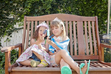 diadema - Girls enjoying ice lolly on garden bench Foto de stock - Royalty Free Premium, Número: 614-08307639