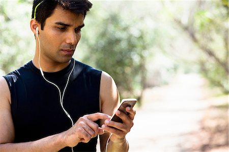 Jogger selecting music on smartphone in park Photographie de stock - Premium Libres de Droits, Code: 614-08307655