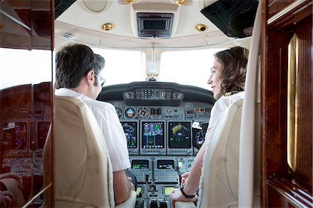Rear view of male and female pilots talking in cockpit of private jet Stock Photo - Premium Royalty-Free, Code: 614-08307846