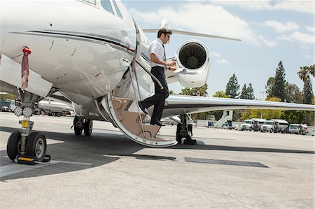 Male private jet pilot stepping from plane at airport Foto de stock - Royalty Free Premium, Número: 614-08307858