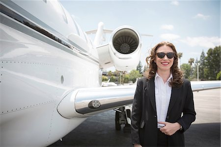 Portrait of mid adult female businesswoman and private jet at airport Foto de stock - Royalty Free Premium, Número: 614-08307853