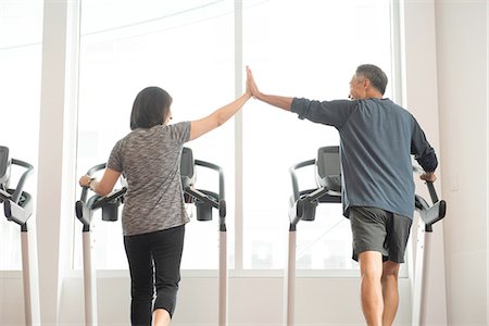 fitness asian couple - Rear view of mature couple on treadmill doing high five Stock Photo - Premium Royalty-Free, Code: 614-08307895