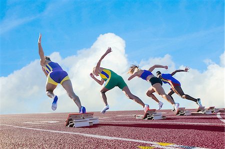 Four female athletes on athletics track, leaving starting blocks, rear view Stock Photo - Premium Royalty-Free, Code: 614-08307954