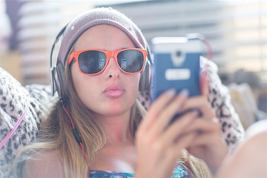 Teenager with sun glasses using smartphone on lazy chair Stock Photo - Premium Royalty-Free, Image code: 614-08329183
