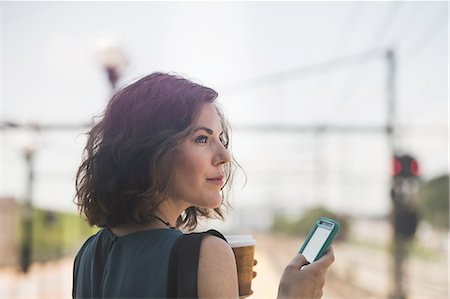 draußen - Mid adult woman waiting at train station, using smartphone, holding coffee cup Stockbilder - Premium RF Lizenzfrei, Bildnummer: 614-08329194