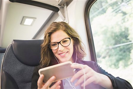 Mid adult woman on train, using smartphone, wearing earphones Stockbilder - Premium RF Lizenzfrei, Bildnummer: 614-08329207