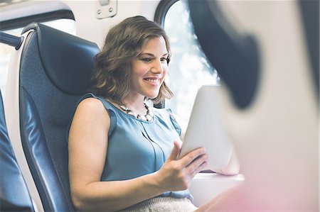 Mid adult woman on train using digital tablet Stock Photo - Premium Royalty-Free, Code: 614-08329216