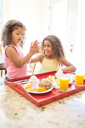 Sisters at home preparing breakfast, doing high five Stock Photo - Premium Royalty-Free, Code: 614-08329317