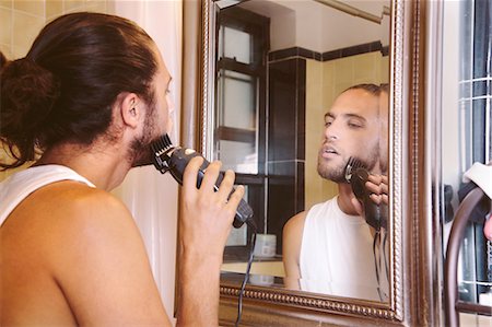 simsearch:614-07146362,k - Young man looking in mirror, shaving with electric razor Fotografie stock - Premium Royalty-Free, Codice: 614-08329386