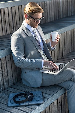 Young businessman typing on laptop on city stair Stock Photo - Premium Royalty-Free, Code: 614-08329504