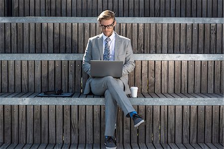 full suit - Suited young businessman typing on laptop on city stair Stock Photo - Premium Royalty-Free, Code: 614-08329502