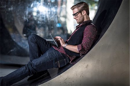simsearch:614-08990534,k - Young businessman reclining on curved wall reading digital tablet touchscreen Foto de stock - Sin royalties Premium, Código: 614-08329517