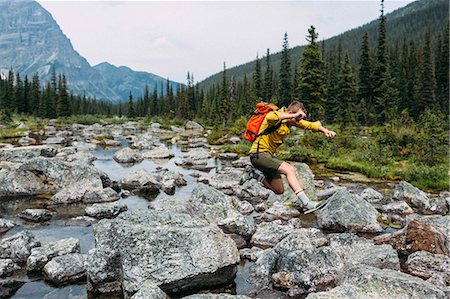 simsearch:649-08662125,k - Side view of mid adult man carrying backpack jumping over rocky riverbed, Moraine lake, Banff National Park, Alberta Canada Foto de stock - Sin royalties Premium, Código: 614-08383511