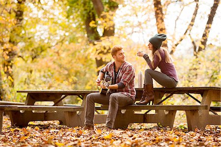 Young couple playing guitar on picnic benches in autumn forest Stock Photo - Premium Royalty-Free, Code: 614-08383592