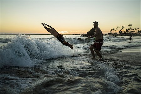 simsearch:614-08383692,k - Young men diving into sea at sunset, Newport Beach, California, USA Foto de stock - Sin royalties Premium, Código: 614-08383691