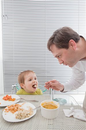 simsearch:6108-06167436,k - Father feeding son at dining table Photographie de stock - Premium Libres de Droits, Code: 614-08392335