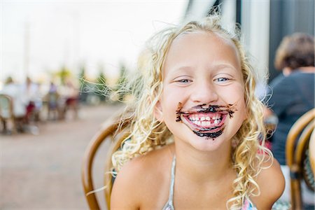 Portrait of blond haired girl at sidewalk cafe with sauce covered mouth Photographie de stock - Premium Libres de Droits, Code: 614-08392439