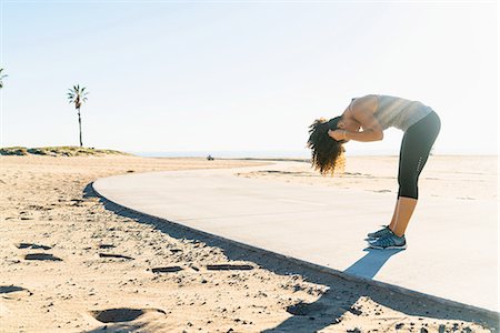 simsearch:614-08392500,k - Mid adult woman standing on pathway at beach, bending over, fixing hair Fotografie stock - Premium Royalty-Free, Codice: 614-08392517